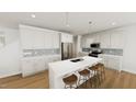 Modern kitchen boasts white cabinetry, stainless steel appliances, a large center island with seating, and stylish pendant lighting at 339 Beacon Dr, Pittsboro, NC 27312