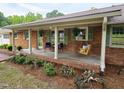 Inviting front porch with a swing, seating area, and lovely landscaping at 3669 W Greensboro Chapel Hill Rd, Liberty, NC 27298