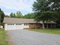 Charming brick ranch-style home with attached garage, mature trees and a gravel driveway at 3669 W Greensboro Chapel Hill Rd, Liberty, NC 27298