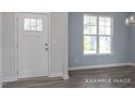 Bright entryway showcasing wood-look flooring, white trim, and a window-lit view of the outdoors at 422 Grading Stick Ct, Angier, NC 27501