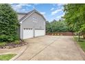 Three-car garage with ample parking space and additional space on the concrete pad next to the fence at 50 Pebble Creek Dr, Franklinton, NC 27525