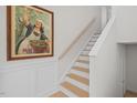 Elegant staircase with white wainscoting, wooden steps and a striking framed vintage poster at 518 Toran Dr, Wake Forest, NC 27587