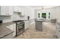 Bright kitchen featuring granite counters, white cabinets, a tile backsplash, and stainless steel appliances at 8312 Bellingham Cir, Raleigh, NC 27615