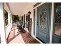 Charming covered porch with brick floor, rocking chairs, and a decorative front door at 9200 Lake Carol Dr, Zebulon, NC 27597