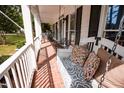 Inviting porch with brick floor, swing with decorative pillows and relaxing seating at 9200 Lake Carol Dr, Zebulon, NC 27597