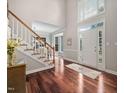 Bright foyer with high ceilings, wood floors, white staircase, and front door with sidelights and transom window at 111 Gingergate Dr, Cary, NC 27519