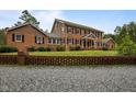 Two-story brick home with a lush lawn, framed by a brick fence and gravel driveway at 12088 Burlington Rd, Hurdle Mills, NC 27541
