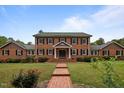 Beautiful two-story brick home featuring a well-maintained lawn and classic architectural details at 12088 Burlington Rd, Hurdle Mills, NC 27541