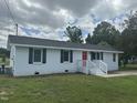 Inviting single-story home with a red front door, crisp white exterior, black shutters, and lush green lawn at 1676 Richardson Bass Rd, Kenly, NC 27542