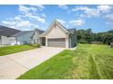 Side view of a one-story home featuring a green lawn and a two-car garage with extended driveway at 1828 Wellspring Ct, Graham, NC 27253