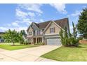 Two-story home featuring a manicured lawn, attached garage, and inviting front porch and long driveway at 2507 Belvinwood Dr, Fuquay Varina, NC 27526