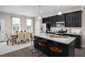 Modern kitchen features an island with countertop seating, granite countertops, stainless steel appliances, and dining area at 700 Tambor Rd, Durham, NC 27713