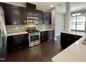 Modern kitchen featuring dark cabinets, stainless steel appliances, and decorative backsplash at 7241 Terregles Dr, Raleigh, NC 27617