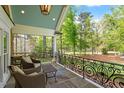 Relaxing covered porch with stone flooring and wrought iron railing overlooks the lush backyard at 801 Pinehurst Dr, Chapel Hill, NC 27517
