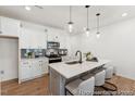 Modern kitchen features an island with seating, pendant lighting, sleek countertops, and stainless steel appliances at 92 Horseshoe Pl # 9, Angier, NC 27501
