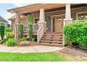 Inviting front porch with brick-based columns, wooden stairs, and lush landscaping enhancing the home's curb appeal at 111 Streamside Dr, Sanford, NC 27330
