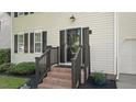 Inviting front entrance featuring brick steps, dark wood railings, and manicured landscaping at 112 Fairford Dr, Holly Springs, NC 27540