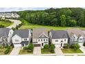 Aerial view of a residential neighborhood with homes backing to a green space with walking path and small pond at 113 Mazarin Ln, Cary, NC 27519