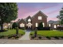 Charming brick home featuring manicured lawn, mature trees and inviting front entrance at dusk at 12140 Pawleys Mill Cir, Raleigh, NC 27614
