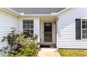 Close-up of the front door with sidelight, black shutters, surrounded by lush plants adding to curb appeal at 1725 E Honey Springs Ave, Fuquay Varina, NC 27526