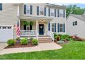 Close-up of inviting front porch with white railings, brick steps, and beautifully landscaped garden at 201 Forbes Rd, Wake Forest, NC 27587