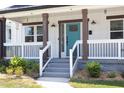 Inviting front porch with white railings, brown columns, and a vibrant teal front door at 2805 Fayetteville St, Durham, NC 27707