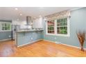 Bright kitchen with stainless steel appliances, white cabinetry, and wood floors at 4030 King Charles Rd, Durham, NC 27707