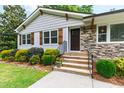 Close-up of the home's entrance, featuring stone accents, well manicured shrubs and new looking front steps at 4906 Lakemont Dr, Raleigh, NC 27609