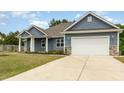 Charming home with blue siding, stone accents, a well-manicured lawn, and attached garage at 565 Joseph Alexander Dr, Fuquay Varina, NC 27526