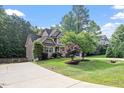 Beautiful two-story home with lush landscaping, mature trees, and a winding driveway on a sunny day at 68 Tanners Way, Clayton, NC 27527