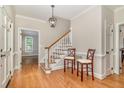 Inviting foyer with hardwood floors, staircase, and elegant lighting fixture at 7801 Wood Way Ct, Raleigh, NC 27606