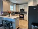 Bright kitchen with white cabinets, stainless steel appliances, a breakfast bar, and modern countertops at 809 Trinity Park Dr, Wake Forest, NC 27587