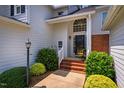 Welcoming home entrance with brick steps, lush landscaping, and a stylish front door at 9 Lake Village Dr, Durham, NC 27713