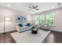 Comfortable living room with neutral tones, plush seating, ceiling fan, large windows, and hardwood flooring at 1049 Lakebrink Dr, Morrisville, NC 27560