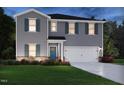 Charming two-story home features gray siding, dark shutters, an attached two-car garage, and green grass at 1138 Winding Spring Dr, Mebane, NC 27302