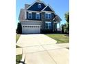 Charming two-story home with blue accents, well-maintained lawn, and a wide driveway leading to an attached two-car garage at 123 Gunderson Ln, Garner, NC 27529