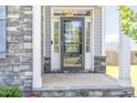 Welcoming front porch featuring a storm door, stone accents, and neutral colored siding at 123 Gunderson Ln, Garner, NC 27529