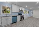 Modern kitchen featuring white cabinets, stainless steel appliances, and plenty of natural light streaming through the windows at 1302 Buffaloe Rd, Garner, NC 27529