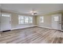 Bright living room featuring beautiful flooring, a ceiling fan, and large windows for natural light at 1592 Boone Rd, Elon, NC 27244