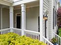 Inviting front porch with classic columns, decorative lighting, and lush landscaping at 1711 Happiness Hill Ln, Raleigh, NC 27614