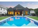A backyard view of the home highlighting a large swimming pool, covered patio, and manicured lawn at 2120 Kipawa St, Raleigh, NC 27607