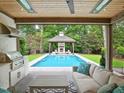 Stylish outdoor living space with a covered patio, grill, and pool with gazebo in background at 2120 Kipawa St, Raleigh, NC 27607