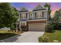 Charming two-story home featuring gray siding, brick accents, a two-car garage, and a well-maintained front yard at 233 Hammond Wood Place, Morrisville, NC 27560
