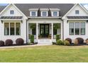Charming front porch with black double doors, columns, and neatly manicured landscaping at 2408 Eddie Howard Rd, Willow Springs, NC 27592