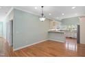 A kitchen area and dining area with hardwood floors, a modern light fixture, and light-colored walls at 2412 Mollynick Lane Ln, Wake Forest, NC 27587
