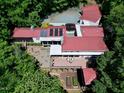 Expansive property with a red roof, wooden deck and lush landscaping seen from above, in a serene setting at 382 Valley Ln, Pittsboro, NC 27312