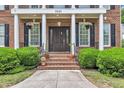 Charming brick home featuring a covered front door, beautiful plants, and meticulous landscaping at 5521 Erinvale Ct, Holly Springs, NC 27540