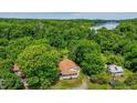 Gorgeous aerial view of a home surrounded by mature trees with a lake and dam in the distance at 5625 Church Rd, Graham, NC 27253