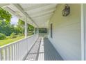 Inviting covered front porch featuring classic white railing and exterior lighting at 5625 Church Rd, Graham, NC 27253