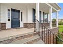Charming front porch with stone accents, a black metal railing, and a dark blue front door at 60 Bold Dr, Youngsville, NC 27596